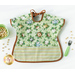 A top down shot of one side of the Toddler bib, showing a light green fabric with tossed jungle animal portraits and staged with a green bowl, fork, and cereal.