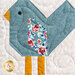 A super close up on a blue bird block, showing patchwork and fabric details. 