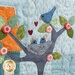 A super close up on the center block of the Blossom Trail wall hanging, showing details on the bluebirds and button embellishments.