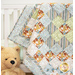 A partial shot of the quilt, shown artfully draped over a white crib and staged with a big teddy bear.