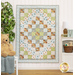 The completed quilt in pastel blues, greens, and earthy browns, hung on a white paneled wall. The quilt is staged with coordinating decor and stuffed animals.