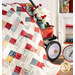 A shot of the draped Frolic quilt, gently laying atop a red wagon carrying coordinating decor.