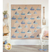 The completed Sailboat quilt in sandy tan and shades of dusty blue, sky blue, and denim, hung on a white paneled wall. Staged with the quilt are coordinating pieces of furniture as well as nautical themed decor.