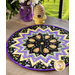 A closer look at the table topper on a wooden table, staged with matching purple and yellow decor.
