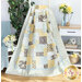 The Easy as ABC and 123 Quilt colored in cream, powder blue, butter yellow, and grey, artfully draped from a white ladder and staged with coordinating furniture and matching decor like flowers, baskets, and books.