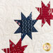 A super close up on three of the pieced sawtooth stars, showing fabric details as well as the top quilting patterns.