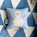 A powder blue pin cushion project with an embellished and detailed snowman on it.