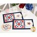 The completed July placemats in a patriotic palette of red, white, and blue, staged on a white table with coordinating teaware and decor.