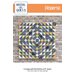 Front cover of pattern, showing the patchwork project without a binding, staged in front of a glazed brick wall.