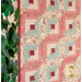 A pink, light blue, and cream Log Cabin Throw Quilt laid flat against the wall next to a green shrub