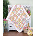 The completed French Roses quilt in the Nature Sings collection from Poppie Cotton, artfully draped over a rustic white armoire staged with coordinating flowers and decor.