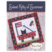 Front of Sweet Kitty of Summer pattern featuring finished mini-quilt displayed on a wooden table.