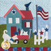 Close up on the center block, a scene depicting a playful dog and charming bluebird outside of a blue house. A US flag waves above a white picket fence.