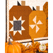 A shot of the wall hanging from a slight angle, showing detail on the patchwork pumpkins and fabrics. Coordinating decor peeks into frame.