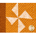 Super close-up of a pinwheel quilt block featuring orange and white geometric fabrics.