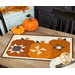 The patchwork pumpkin trio project staged as a table runner on a light wood table with coordinating fall decor.