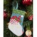 The completed Santa stocking, hung on a green Christmas tree decorated with red and green bulbs.