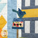 A super close up on the laser cut blue bird and bird house, demonstrating fabric and top quilting details.
