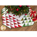 The finished tree skirt in a pleasing array of red and green displayed underneath a decorated Christmas tree with coordinating gift decor placed underneath the tree.