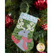 The completed Reindeer stocking, hung on a green Christmas tree decorated with red bulbs.