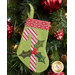 The completed candy cane stocking, hung on a green Christmas tree decorated with red bulbs.