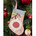 The completed ornament stocking, hung on a green Christmas tree decorated with red bulbs.