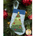 The completed Christmas Tree stocking, hung on a green Christmas tree decorated with red bulbs.