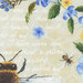 A honeybee and a bumblebee among blue and yellow flowers, with faint handwritten text in the background.