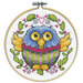 A closeup of the finished Owl cross stitch inside a wooden hoop isolated on a white background.