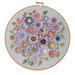 A wooden hoop with a patch of mid-sized embroidered flowers using different types of thread and materials.