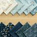 The eleven fabrics included in the Beach House Oops Kit, artfully overlapping each other on a light wood countertop. 