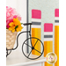 A stylized shot of a decorative wire bicycle with a basket of coordinating pink and yellow flowers; the September door banner can be seen out of focus in the background.