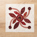 A quilt block with a circle center leaves, and swirled trailing berries on a wood table