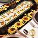 A close up of the table runner on a white table showing detail on the sunflower and butterfly fabrics and staged with coordinating plates and glassware. 