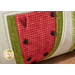 A super close up on the center applique watermelon of the pillow, demonstrating details on the black seed buttons.