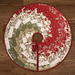 A top down shot of the tree skirt, demonstrating the full effect of the Bargello design, isolated on a dark wood grain background.