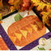 A close up shot of a pumpkin in a flying geese design, surrounded by colorful yellow fall leaves with artful shadows and lighting cast across the project.