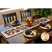 The completed Pumpkin Lane Table Runner staged atop a brown table, set with coordinating plates, napkins, and a basket of matching flowers and decor. 