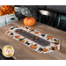 A table setting featuring the completed table runner with black cats and pumpkins and staged with coordinating decor.