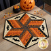 A hexagonal quilted table centerpiece project featuring Halloween colors and applique bats, and a decorative cauldron of candy corn.