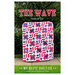 The front of The Wave pattern featuring the finished quilt being held up in front of a set of trees.