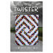 The front of the Twister pattern featuring the finished quilt being held up by someone in front of an oncoming storm past a field in the background.