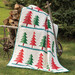 A shot of a pieced tree themed quilt, staged outdoors on a wheelbarrow of chopped wood.