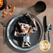 A top down shot of a place setting with the reversible Halloween fabric of the napkin faced out.