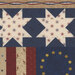 Quilt pattern featuring blue and cream stars with red and beige stripes, plus yellow stars on a dark background.