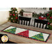 The Tree Farm Table Runner colored in red, cream, and green fabrics from the Winterly collection, staged on a rustic wood table with coordinating trees, garlands, and decor.