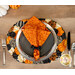 A top shot of the decorative pumpkins oval placemat set with plates and silverware topped with a coordinating Hallow's Eve cloth napkin.