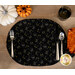 A top shot of the glowing cat eyes oval placemat set with silverware, surrounded by coordinating Halloween decor.