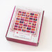 A top down shot of the quilt kit in its keepsake box, brightly colored in pink, peach, and purple.