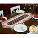 The completed Easy Striped Table Runner, colored in cream and brown fabrics from the Baking Up Joy collection, displayed on a wooden table and staged with coordinating tableware. A decorated Christmas tree can be seen in the background.